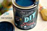 Open can of DIY Paint Co. Bohemian Blue with its lid and a paintbrush nearby.