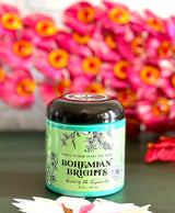 DIY Paint Co. Bohemian Brights jar on a surface, vivid pink flowers softly blurred in the background.