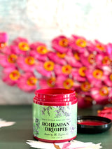 Open jar of Bohemian Brights by DIY Paint Co. on a surface with pink flowers nearby.