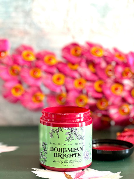 Open jar of Bohemian Brights by DIY Paint Co. on a surface with pink flowers nearby.