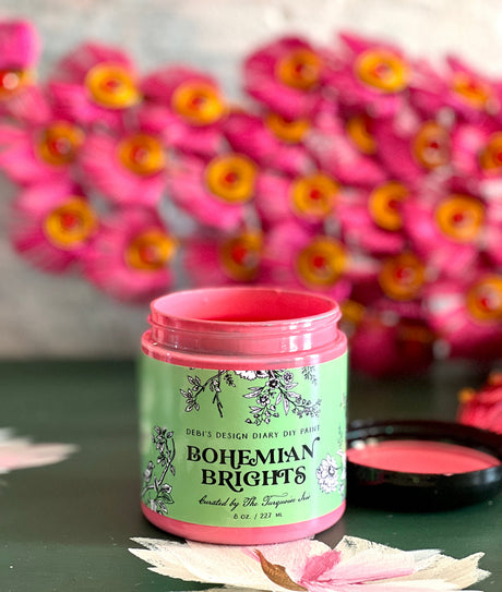 Open jar of Bohemian Brights by DIY Paint Co. on a table, pink flowers softly blurred in the background.