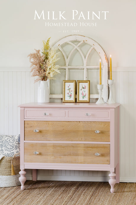 Pink and wood dresser painted with Homestead House Bouquet Milk Paint, decorated with candles and a white arched mirror.