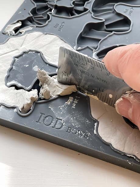 Hand leveling clay with a metal ruler in the Bows Mould by IOD, Iron Orchid Designs. Brand: I.O.D.