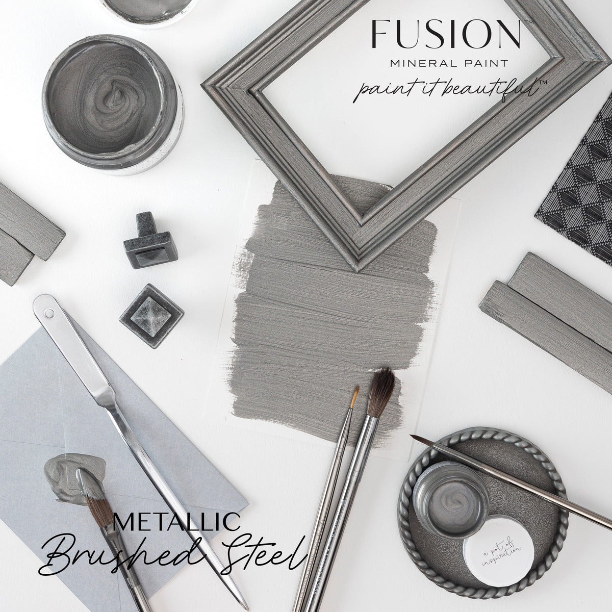 Fusion Mineral Paint brushes, swatch, frames, and Brushed Steel Metallic paint cans arranged on a white surface.