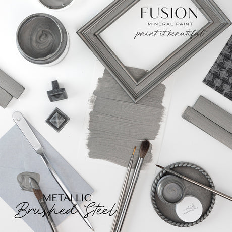 Fusion Mineral Paint brushes, swatch, frames, and Brushed Steel Metallic paint cans arranged on a white surface.