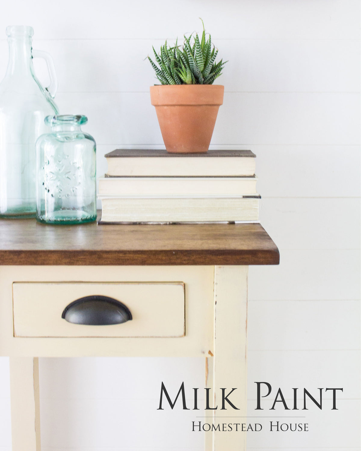Buttermilk Cream Milk Paint by Homestead House on a vintage table with potted plant, glass bottles, and books.