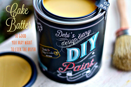 Open can of Cake Batter DIY Paint by DIY Paint Co. with brush on white surface.