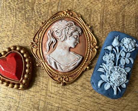 Red heart brooch, I.O.D. Cameos Mould cameo brooch, and blue brooch with white flowers.