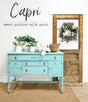 Vintage dresser painted in Old Fashioned Milk Paint’s Capri, placed near a door with a wreath and “Capri” sign above.