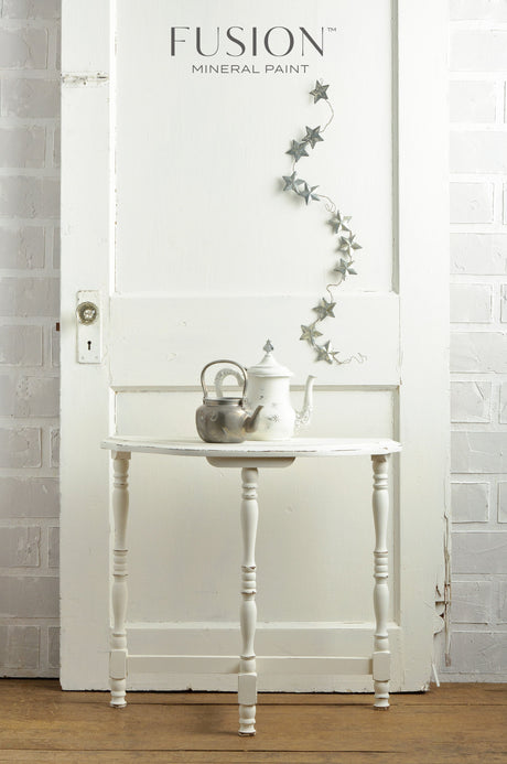 White table with teapots and a star garland, in front of a Casement by Fusion Mineral Paint wall.
