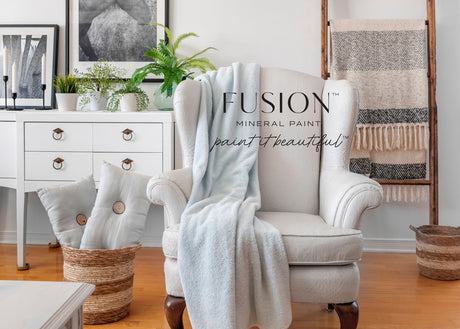 White armchair with blue blanket against Cashmere Fusion Mineral Paint wall; nearby basket, desk, art, and ladder.