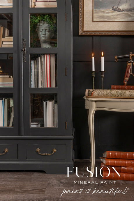 Fusion Mineral Paint Cast Iron cabinet with books and a bust; nearby table holds candles and a map.