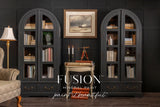 Two black arched bookshelves painted with Fusion Mineral Paint’s Cast Iron, displaying books and art.