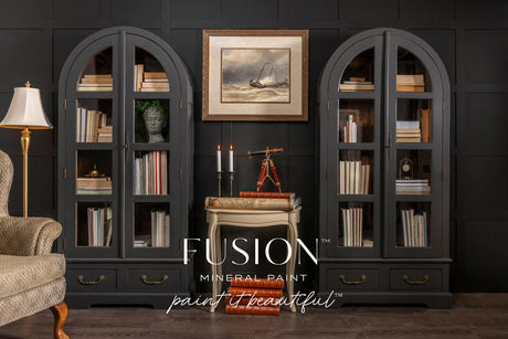 Two black arched bookshelves painted with Fusion Mineral Paint’s Cast Iron, displaying books and art.