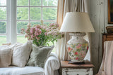 Floral lamp on rustic table with I.O.D. Catharina Transfer beside white sofa and pink flowers.