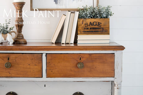 Dresser in Homestead House Cathedral Taupe Milk Paint with books and decor on top against a white shiplap wall.