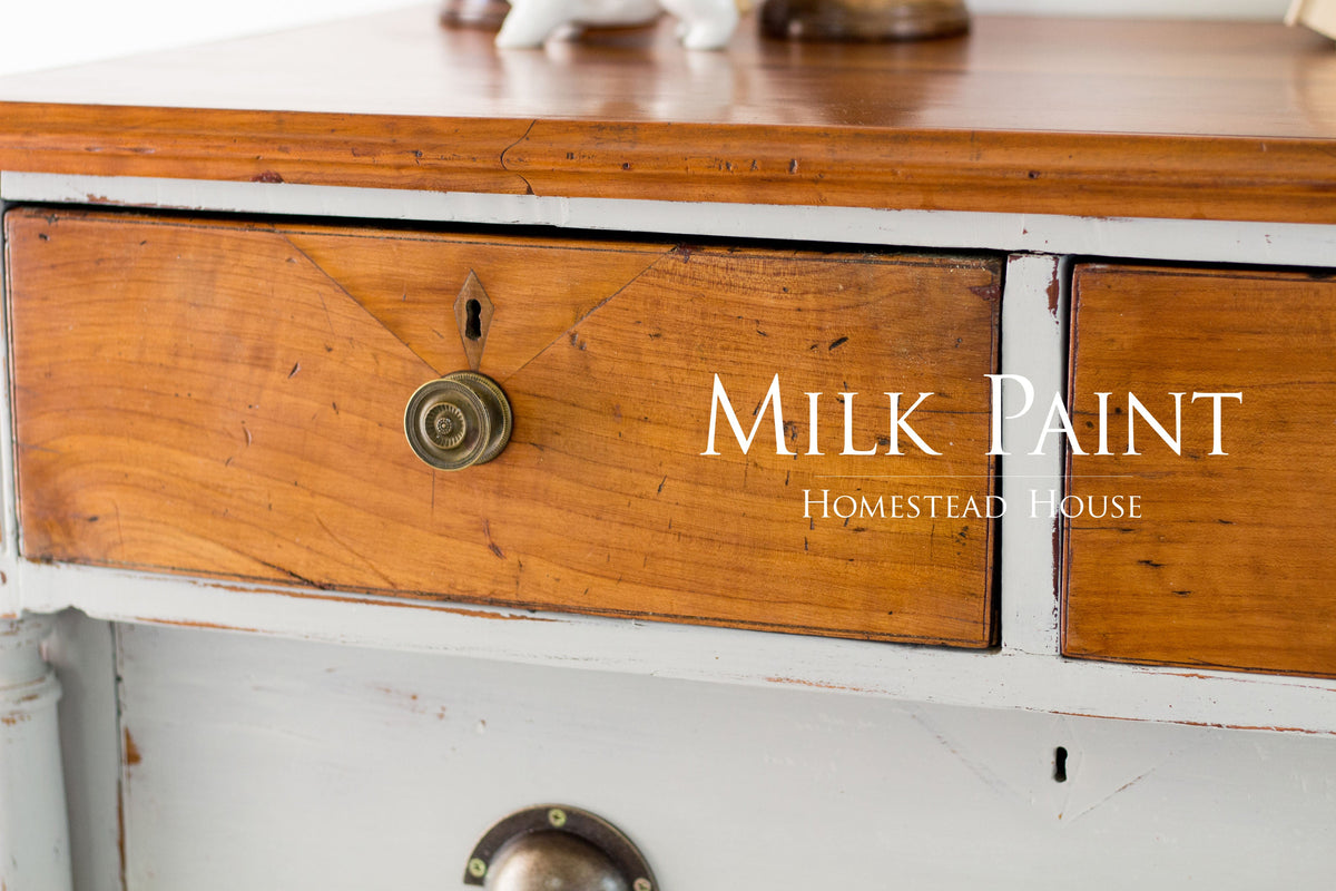 Wooden drawer with round knob, featuring “Cathedral Taupe Milk Paint by Homestead House” text on the front.