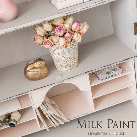 Cathedral Taupe Milk Paint by Homestead House on a white shelf with dried roses, gold bird, and letters.