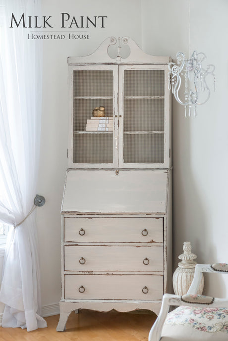White distressed cabinet with glass doors, painted Homestead House Cathedral Taupe Milk Paint.