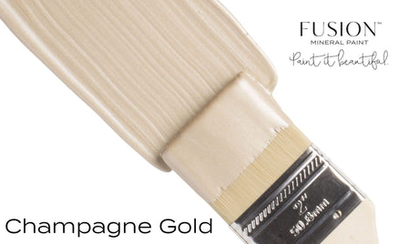 Brush with Champagne Gold Metallic Fusion Mineral Paint, shimmering on a white background.