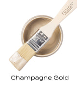 Open can of Fusion Mineral Paint, Champagne Gold Metallic, with brush and label reading “Champagne Gold.”.