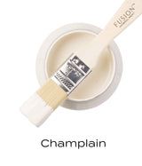 Paintbrush with warm white paint resting on open jar of Champlain Fusion Mineral Paint by Fusion Mineral Paint.