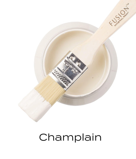 Paintbrush with warm white paint resting on open jar of Champlain Fusion Mineral Paint by Fusion Mineral Paint.