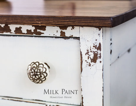 White drawer with chipped Champlain Milk Paint by Homestead House, decorative knob, brand text underneath.