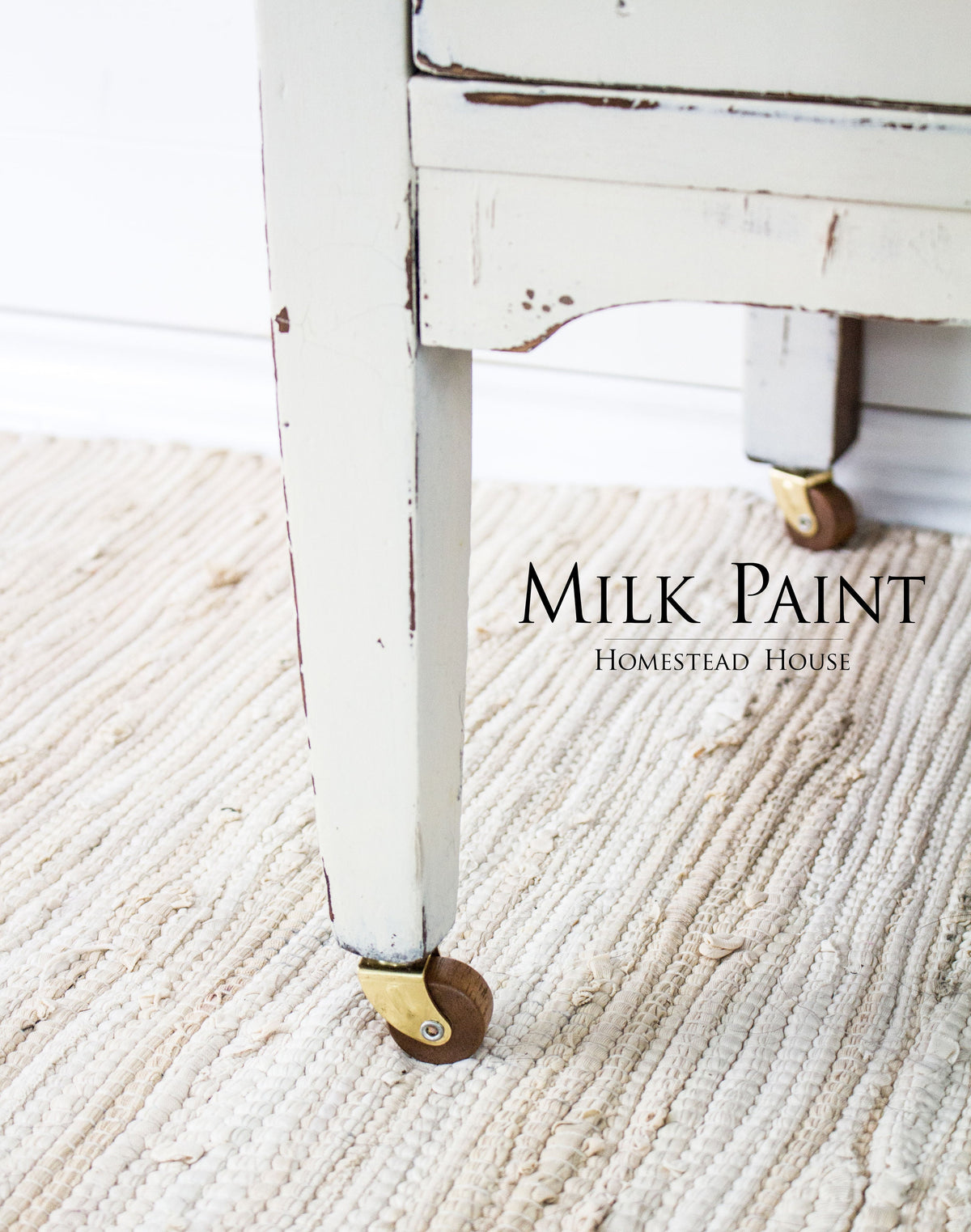 Distressed white table leg in Champlain Milk Paint by Homestead House with brass caster wheels.