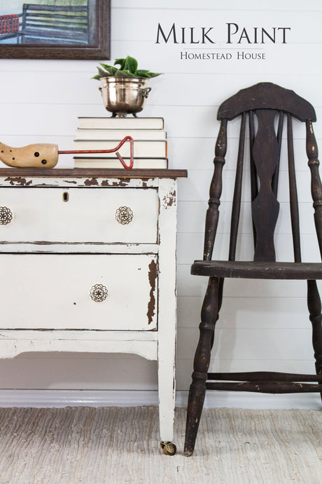 Rustic chair and dresser in Homestead House Champlain Milk Paint beside books, plant pot, and toys on a rug.