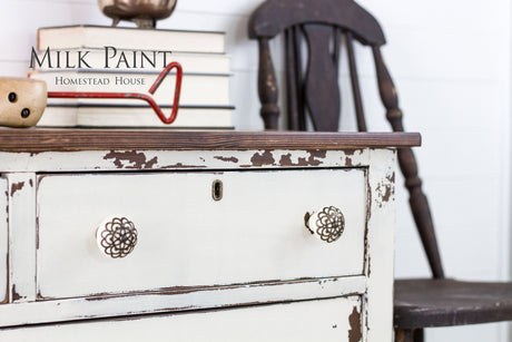 Distressed white dresser in Homestead House Champlain Milk Paint with ornate knobs.