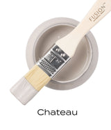 Fusion Mineral Paint in Chateau, a warm neutral grey, with a paintbrush resting on its open container.