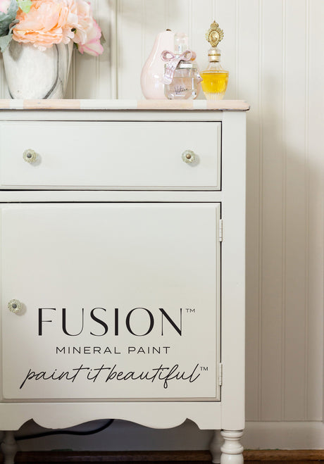 White dresser painted in Chateau Fusion Mineral Paint, warm neutral grey, with “paint it beautiful” on the door.