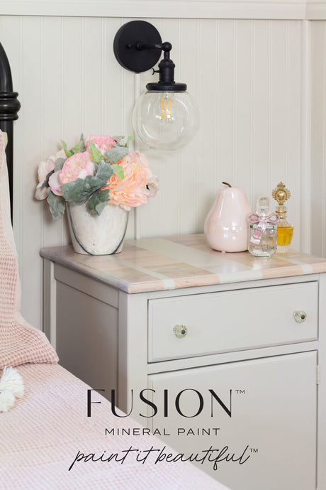 Nightstand painted in Fusion Mineral Paint’s Chateau with a vase, pink pear, and perfume bottles on top.