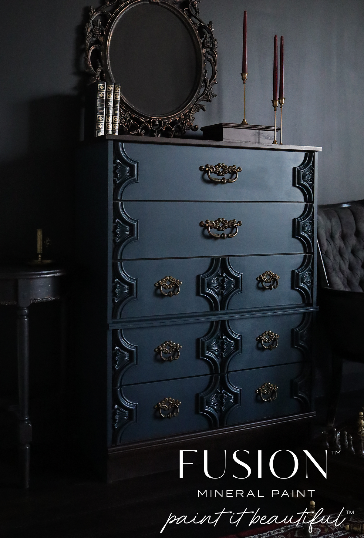 Matte dark blue dresser in Chestler Fusion Mineral Paint with brass handles, styled with books.