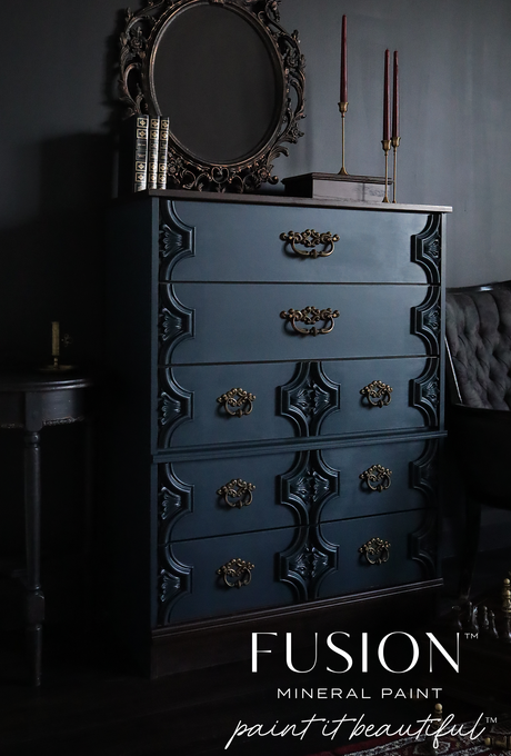 Matte dark blue dresser in Chestler Fusion Mineral Paint with brass handles, styled with books.