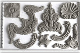 Gray plaster ornaments made with Classic Elements Mould by IOD on a plain background.