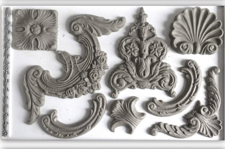 Gray plaster ornaments made with Classic Elements Mould by IOD on a plain background.