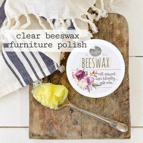 Clear Beeswax Furniture Polish by Old Fashioned Milk Paint next to wax on a board with a striped cloth nearby.