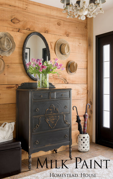 Black antique dresser painted in Homestead House Coal Black Milk Paint, styled with tulips, hats, and umbrellas.