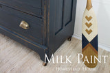 Blue dresser painted with Coal Black Milk Paint by Homestead House, shown next to a paddle on a rug.