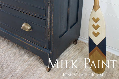 Blue dresser painted with Coal Black Milk Paint by Homestead House, shown next to a paddle on a rug.