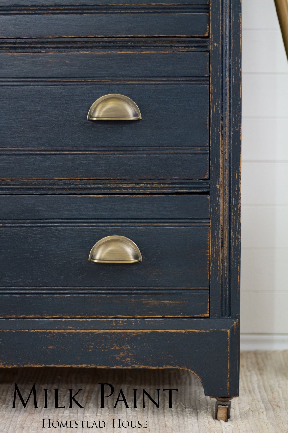 Navy blue dresser with brass pulls, distressed edges, and “Milk Paint” text; painted in Homestead House Coal Black.