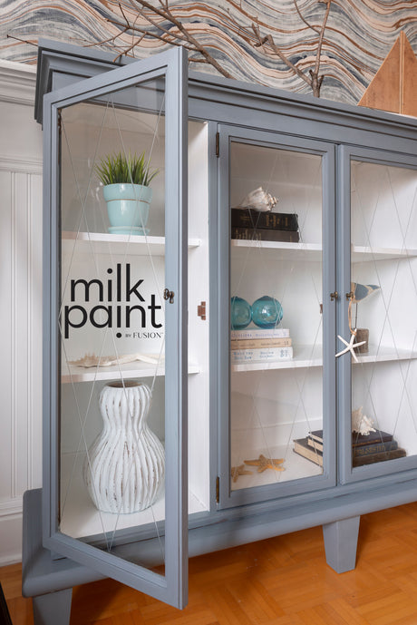Display cabinet painted Coastal Blue by Fusion Mineral Paint, with glass doors showing books and decor inside.