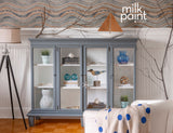 Gray cabinet in Coastal Blue Milk Paint displaying vases on wood floors with nautical-themed decor.