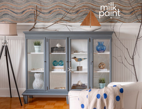 Gray cabinet in Coastal Blue Milk Paint displaying vases on wood floors with nautical-themed decor.