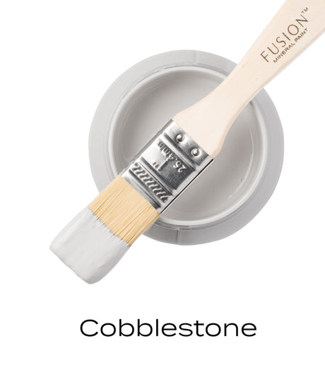 Brush on Cobblestone Fusion Mineral Paint jar; “Cobblestone” shown below in warm grey paint.