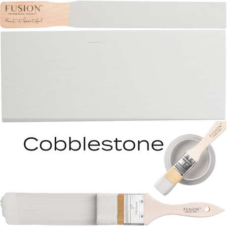 Paintbrush with warm grey paint, wooden board, and Fusion Mineral Paint can labeled Cobblestone.