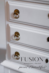 Dresser drawers with brass handles, painted in Fusion Mineral Paint’s Cobblestone; logo at lower right corner.