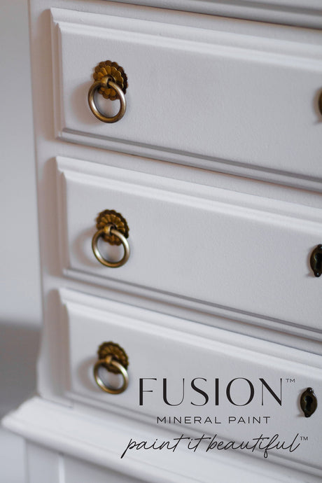 Dresser drawers with brass handles, painted in Fusion Mineral Paint’s Cobblestone; logo at lower right corner.